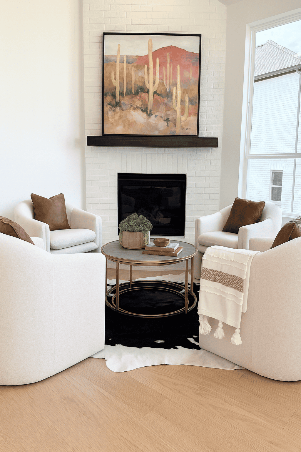 Cozy sitting area with four white armchairs gathered around a coffee table in front of a white brick fireplace.
