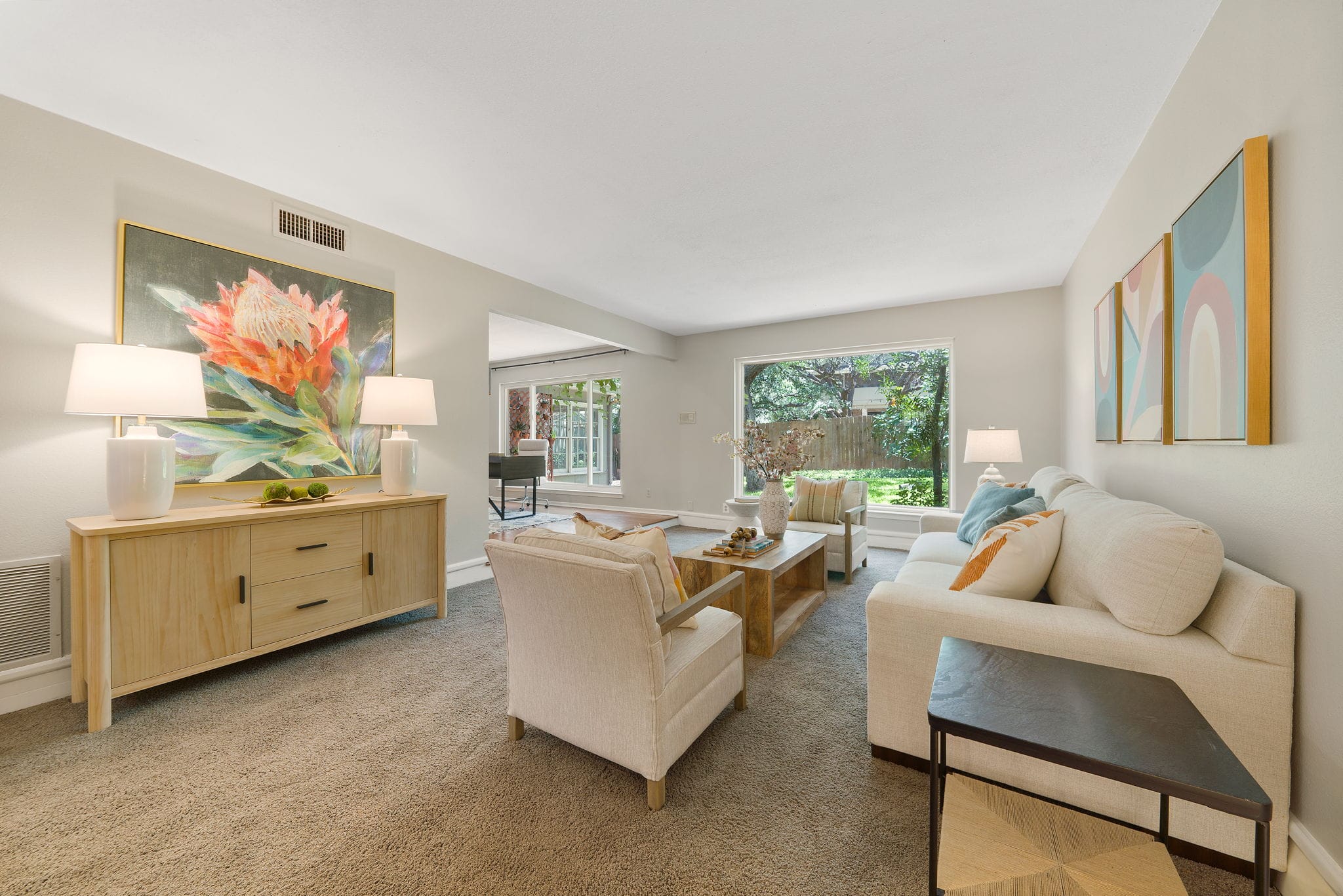Home staging living room showcasing neutral furniture, statement artwork, soft lighting, and an open, buyer-friendly layout