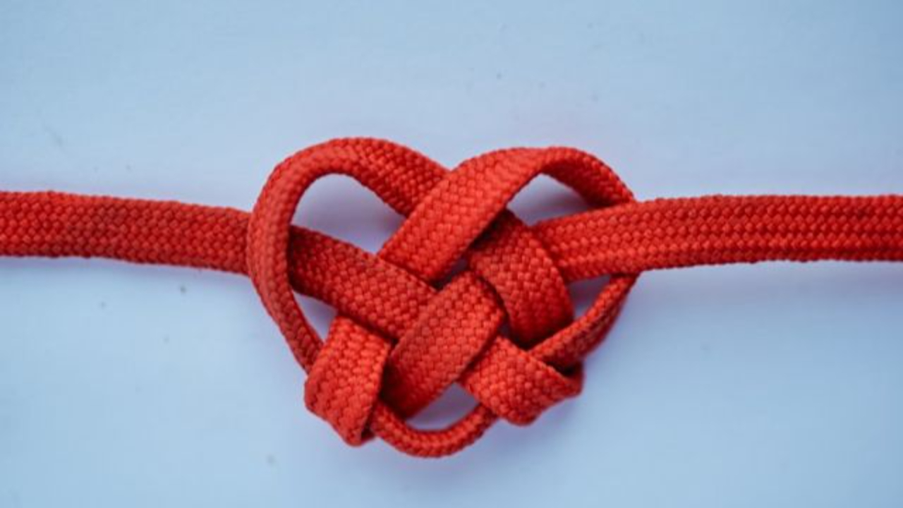 Navigating difficult client conversations blog: A blue background with a red heart made out of rope