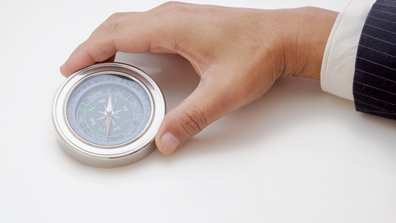 A hand trying to twist a compass, symbolizing external pressure to change direction
