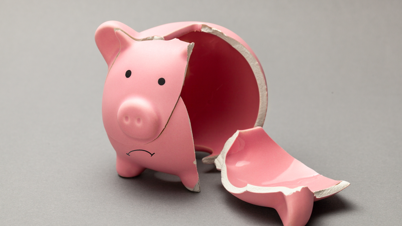 Broken pink piggy bank on a grey background, symbolising running out of money or being unable to raise funds.