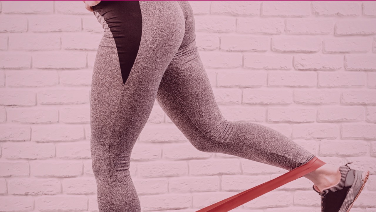 kvinne gjør kontrollert kickback med strikk som riktig glute-aktiveringsøvelse