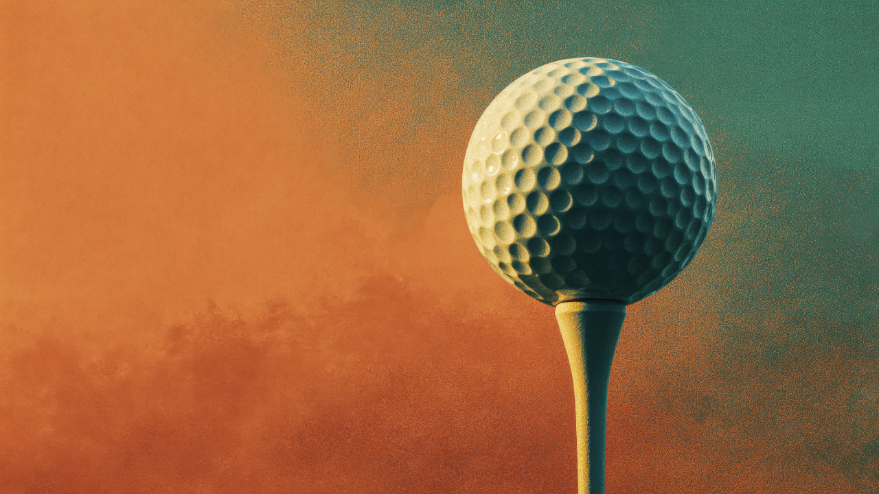 Golf ball on a tee with the sunset orange sky in the background