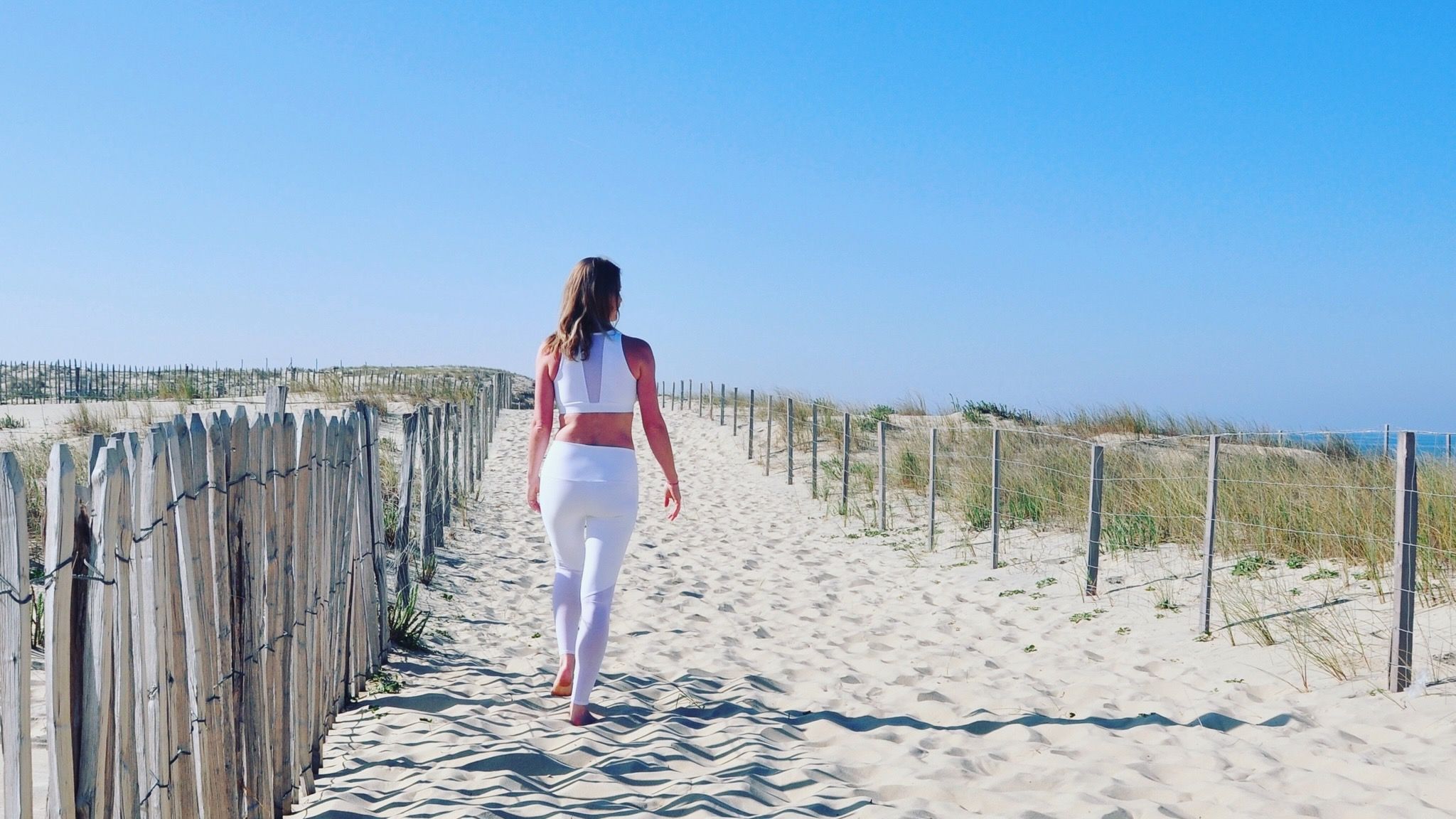 Femme marchant seule sur un chemin de sable, symbole d’autonomie et de chemin intérieur dans la philosophie du yoga