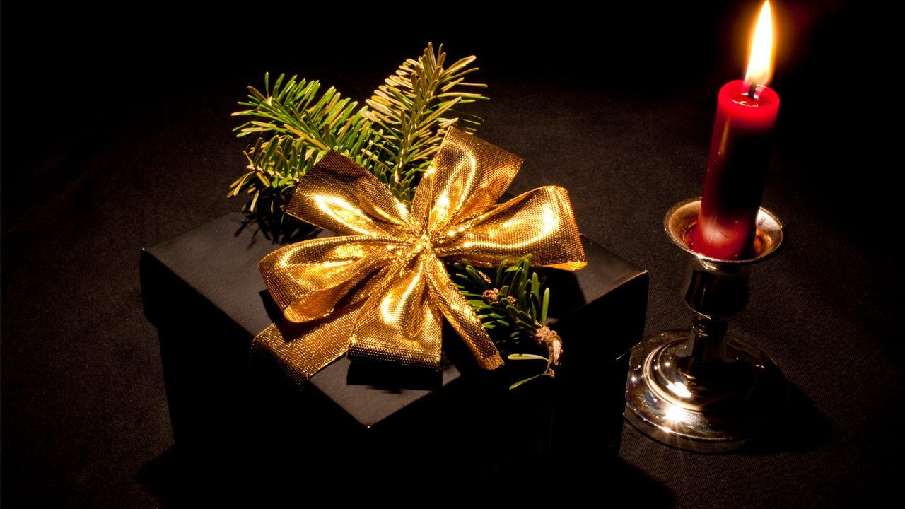A wrapped gift box next to a cozy lit candle.