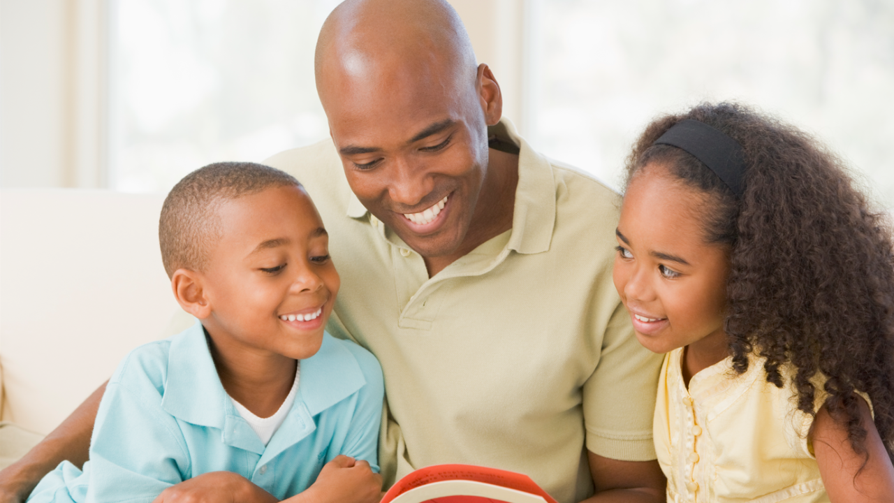 A black father reading to his two children