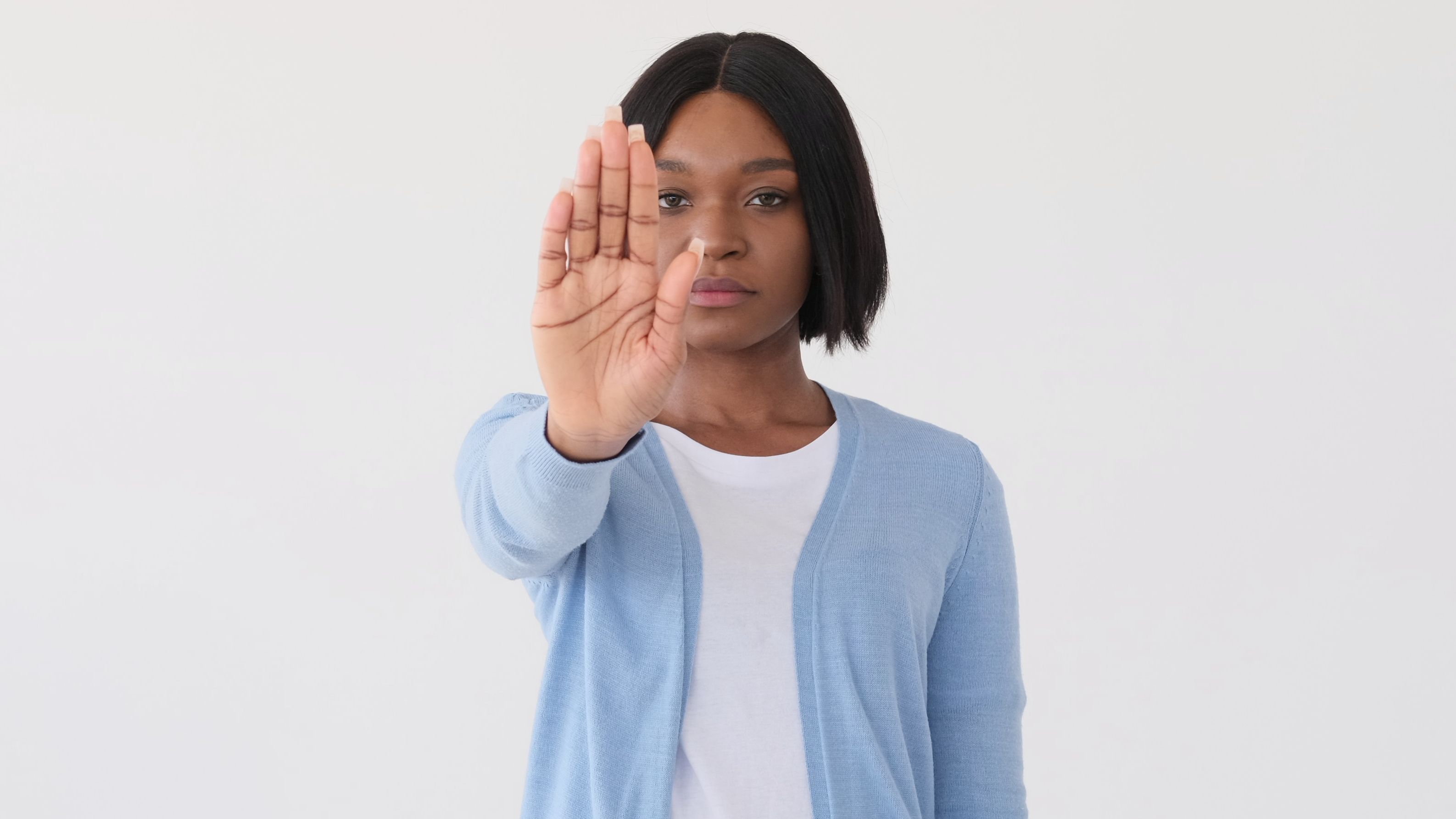 A young woman holds up her hand to the camera in a 