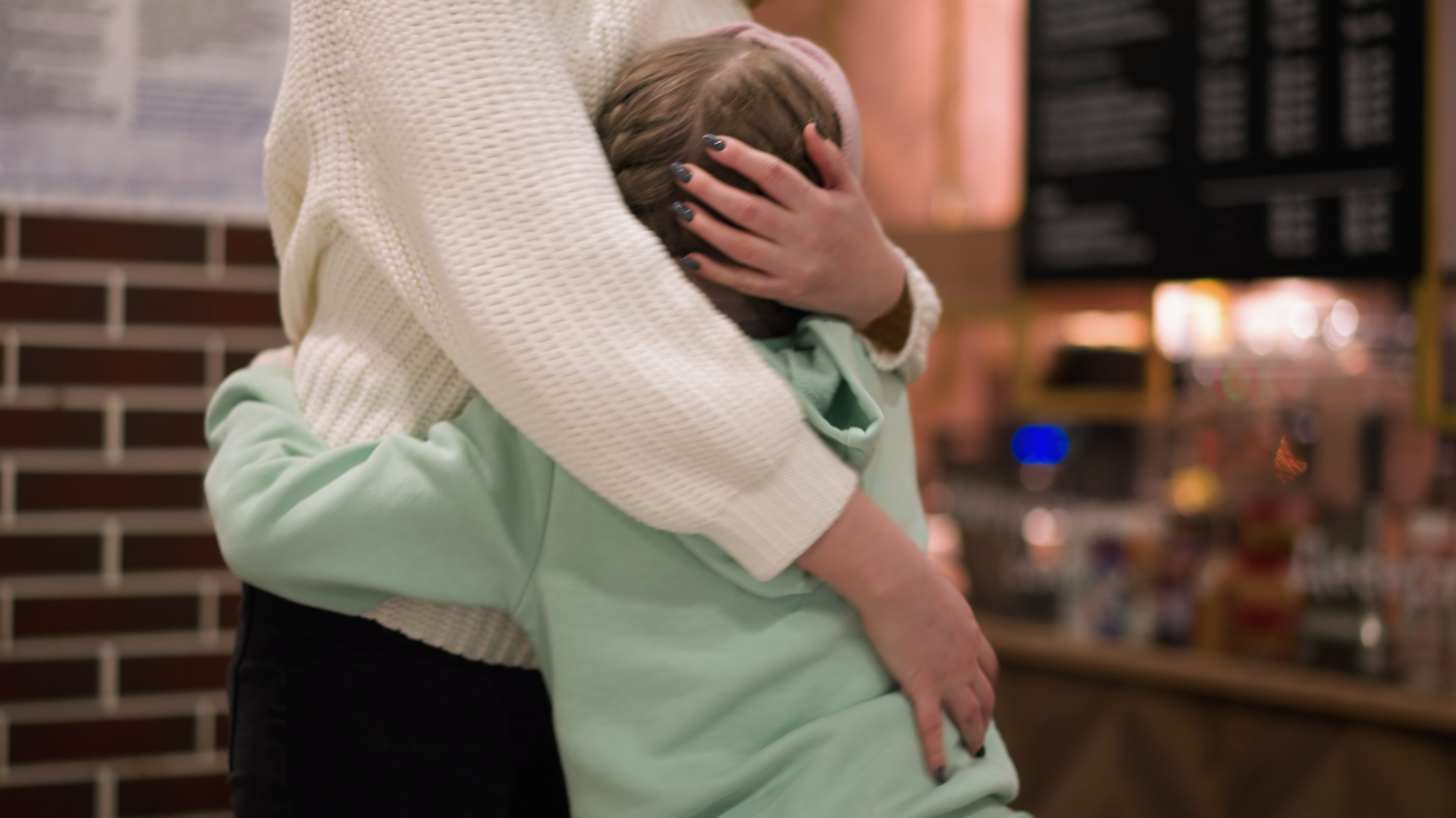 A child being hugged by their mother.