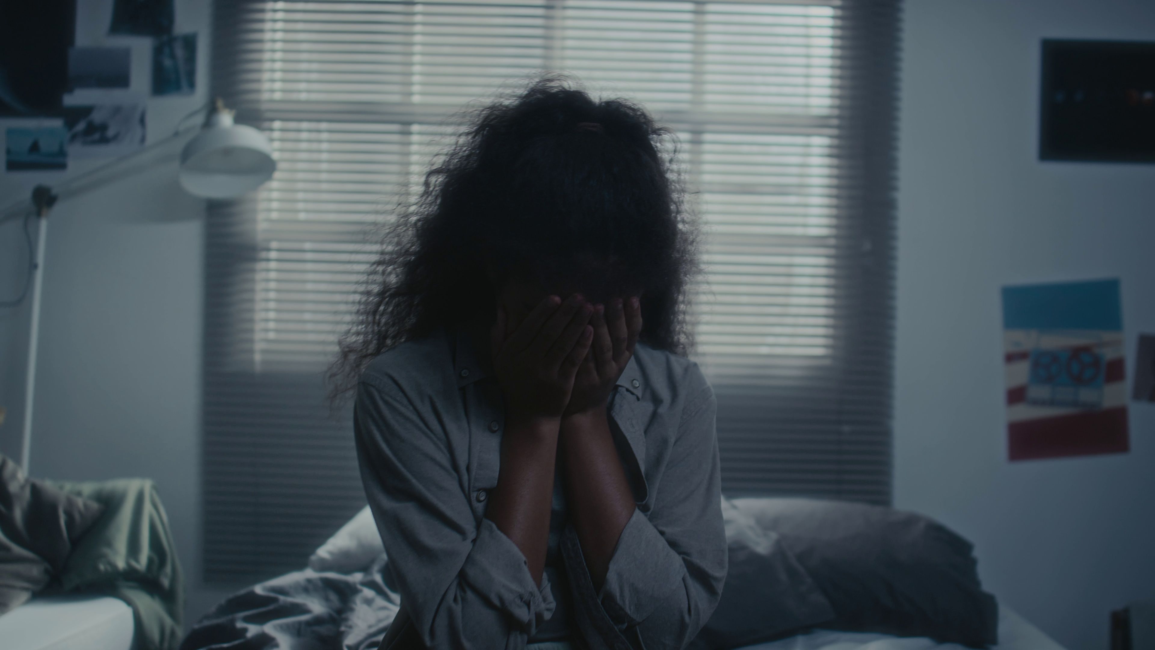 A teenage girl sits with her head in her hands.
