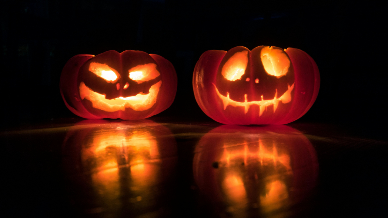 Two lit up carved pumpkins with creepy smiles.
