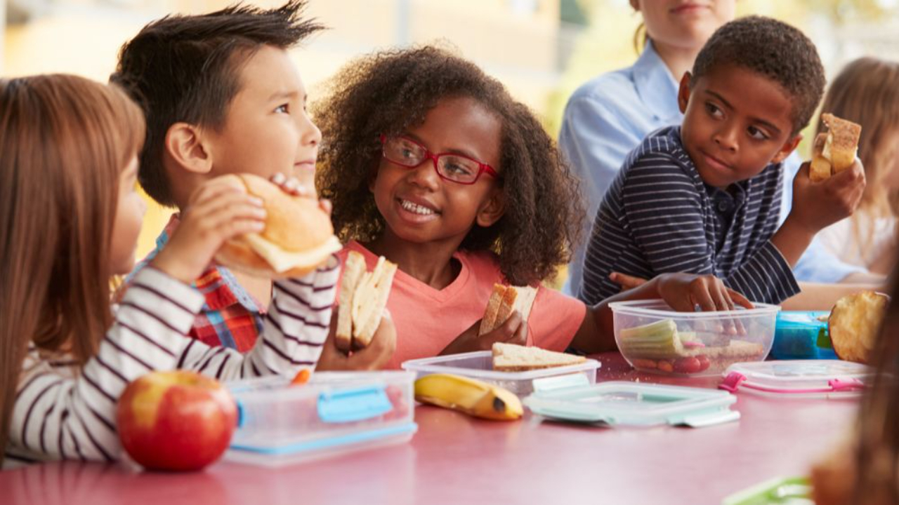 Children laughing sitting at a lunch table together