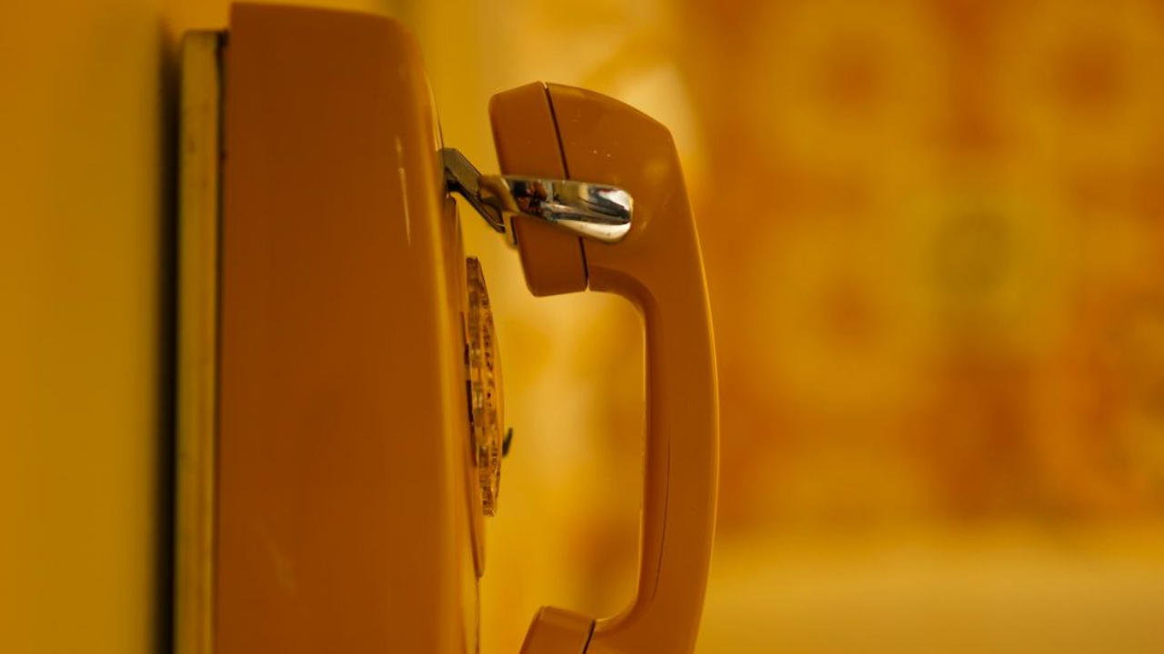 an orange phone is hanging on a wall