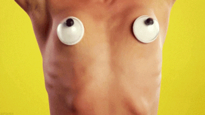 cropped image of a topless woman's chest with googley eyes covering breasts