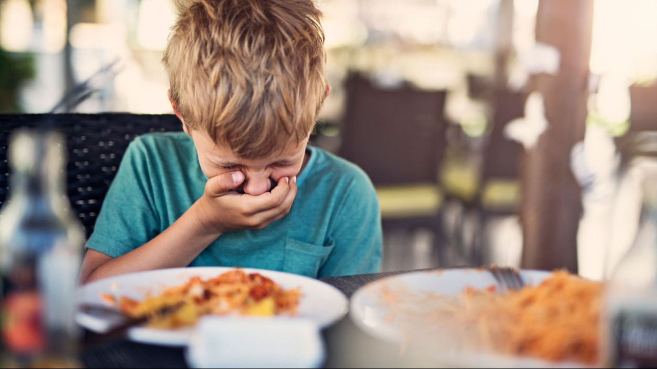 boy gagging while sitting with food at the table