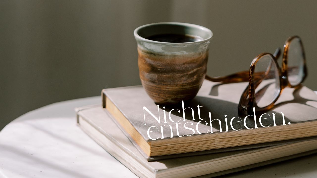 Kaffeebecher und Brille auf einem Stapel Bücher