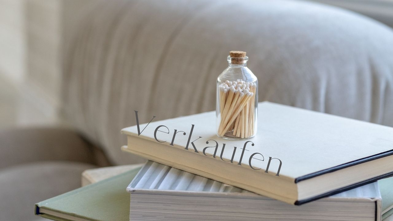 Bücherstapel neben einer Couch auf dem eine durchsichtige Glasflasche mit Streichhölzern steht