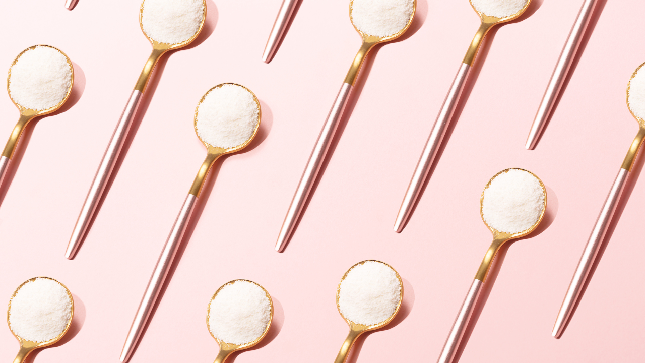 several gold teaspoons on a pale pink background, each of them filled with white protein powder