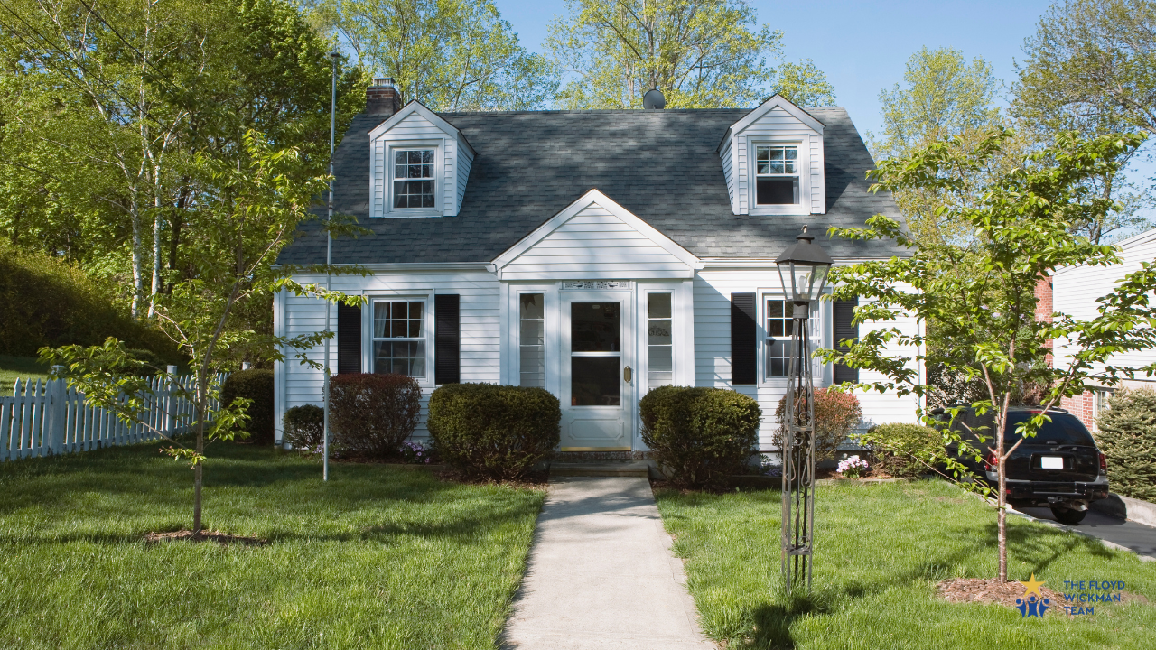 White house with dormers and green grass and trees out front