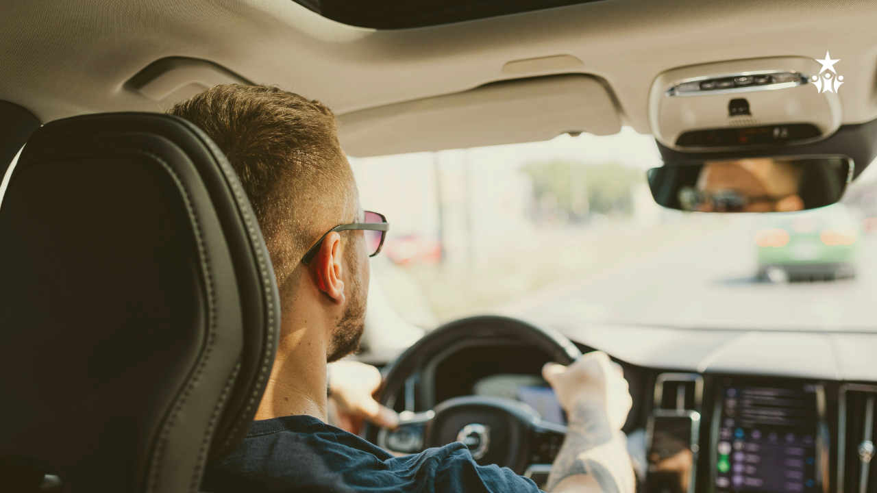 a man with glasses and short hair driving a car