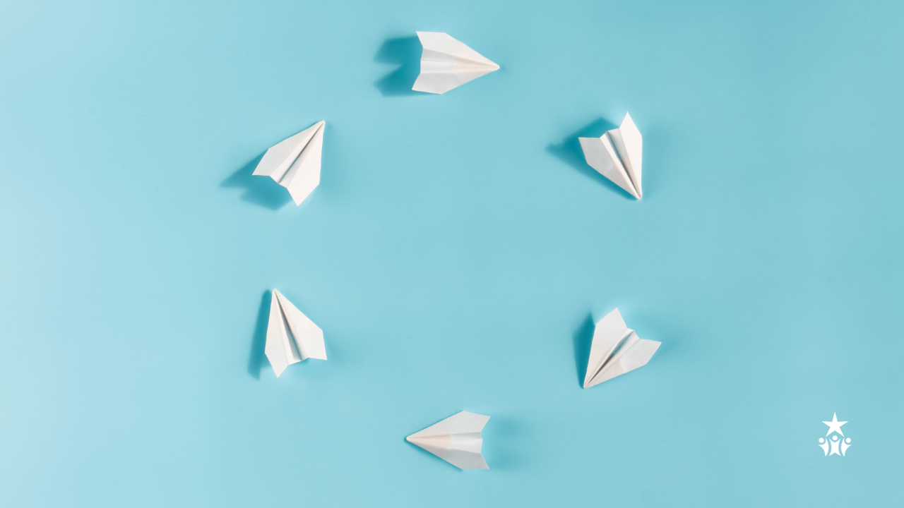 blue background with little white paper airplanes forming a circle in the middle