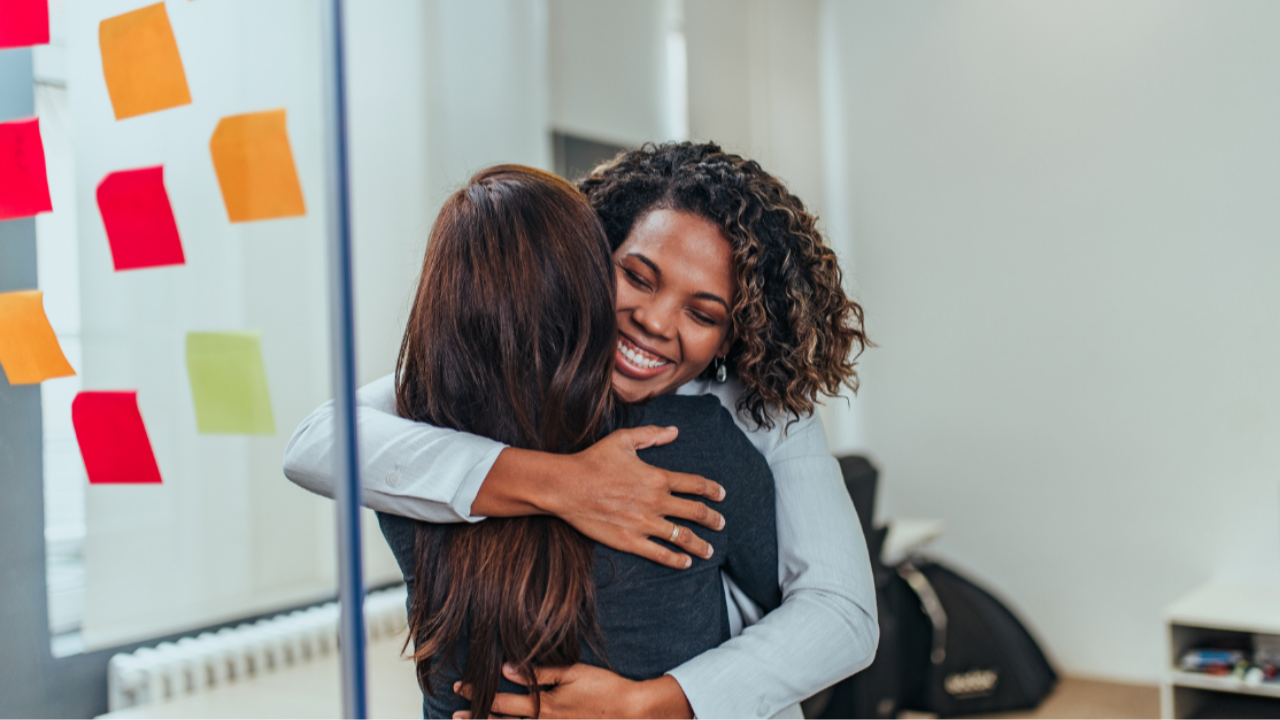 A photo of two women hugging at the office 