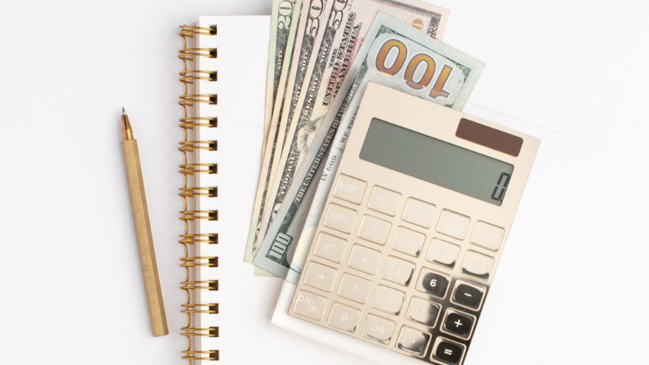 golden calculator, $100 bills, and notebook