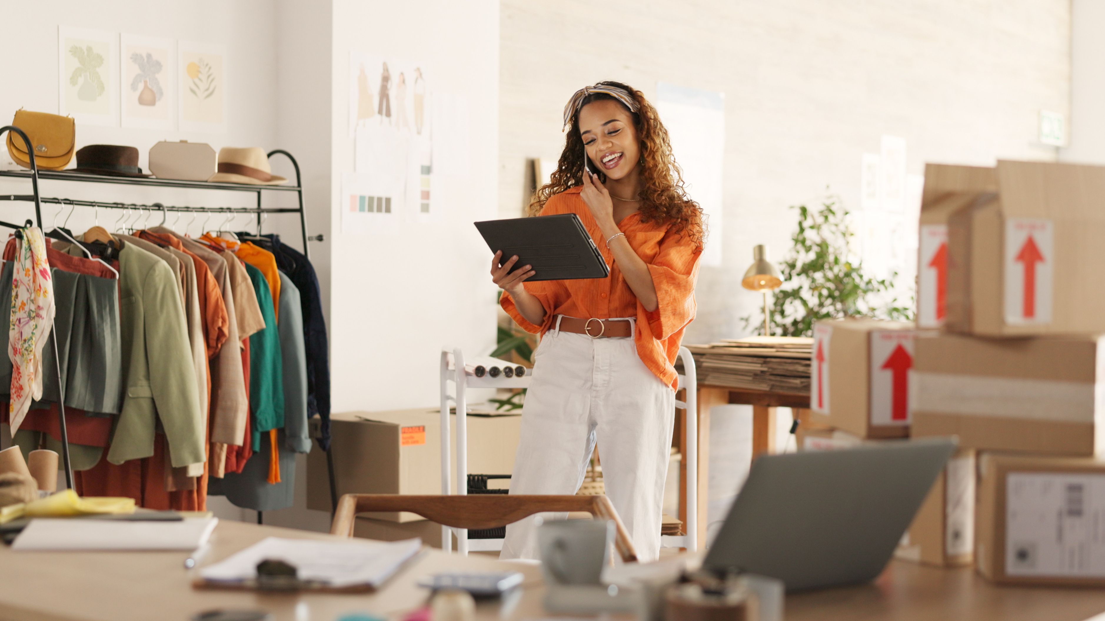 small business owner, talking on the phone, typing on an iPad, in a clothing shop