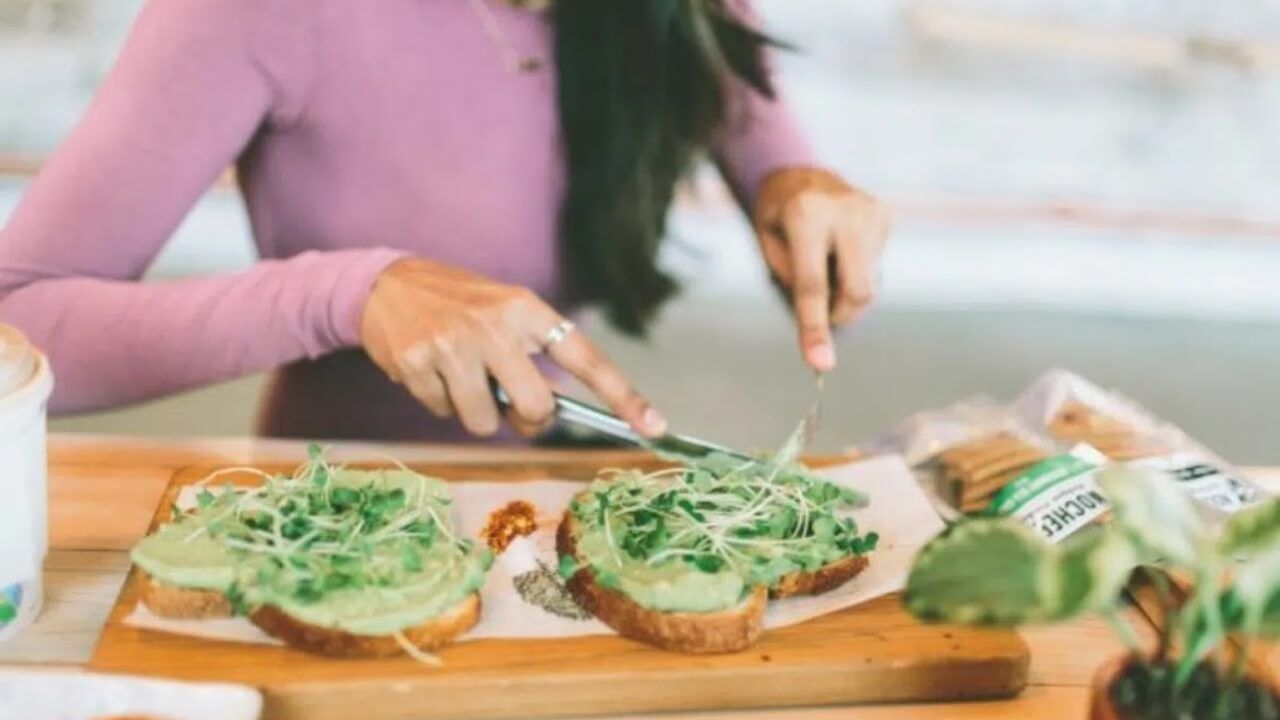 A woman eats avocado toast, one of the best foods to get you pregnant