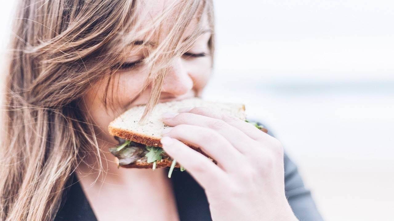 A woman takes a bite out of a sandwich, eating enough to get pregnant