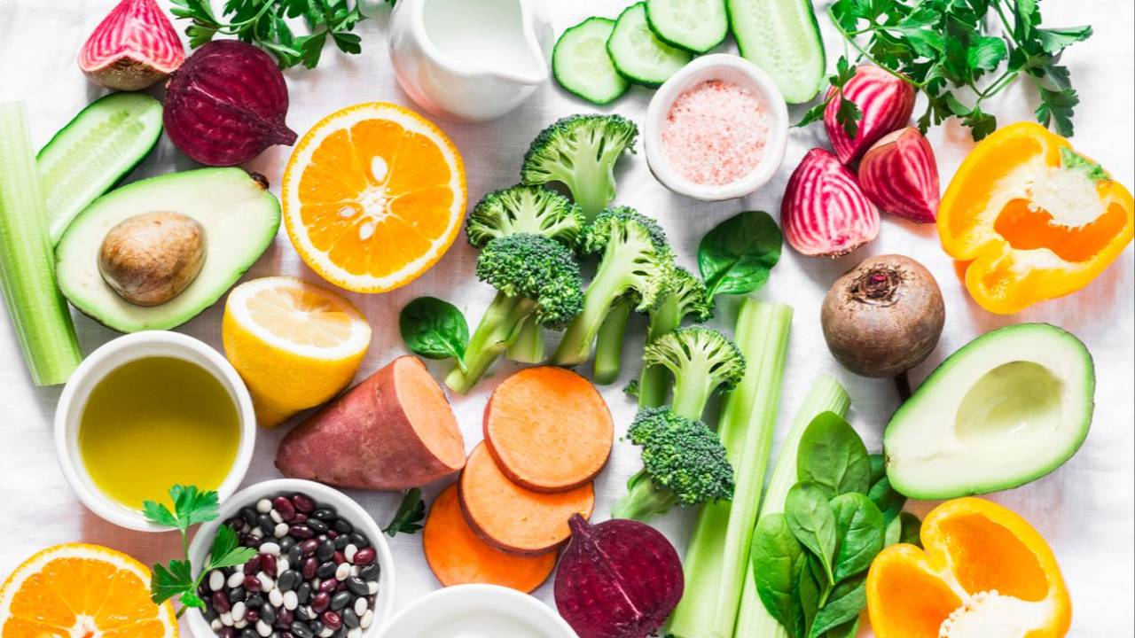 Colorful flat lay of anti-aging foods—berries, leafy greens, salmon, citrus, avocado—promoting youthful skin for women over 50.