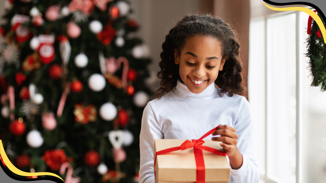 a teen opening up a Christmas Present in front of a Christmas Tree 
