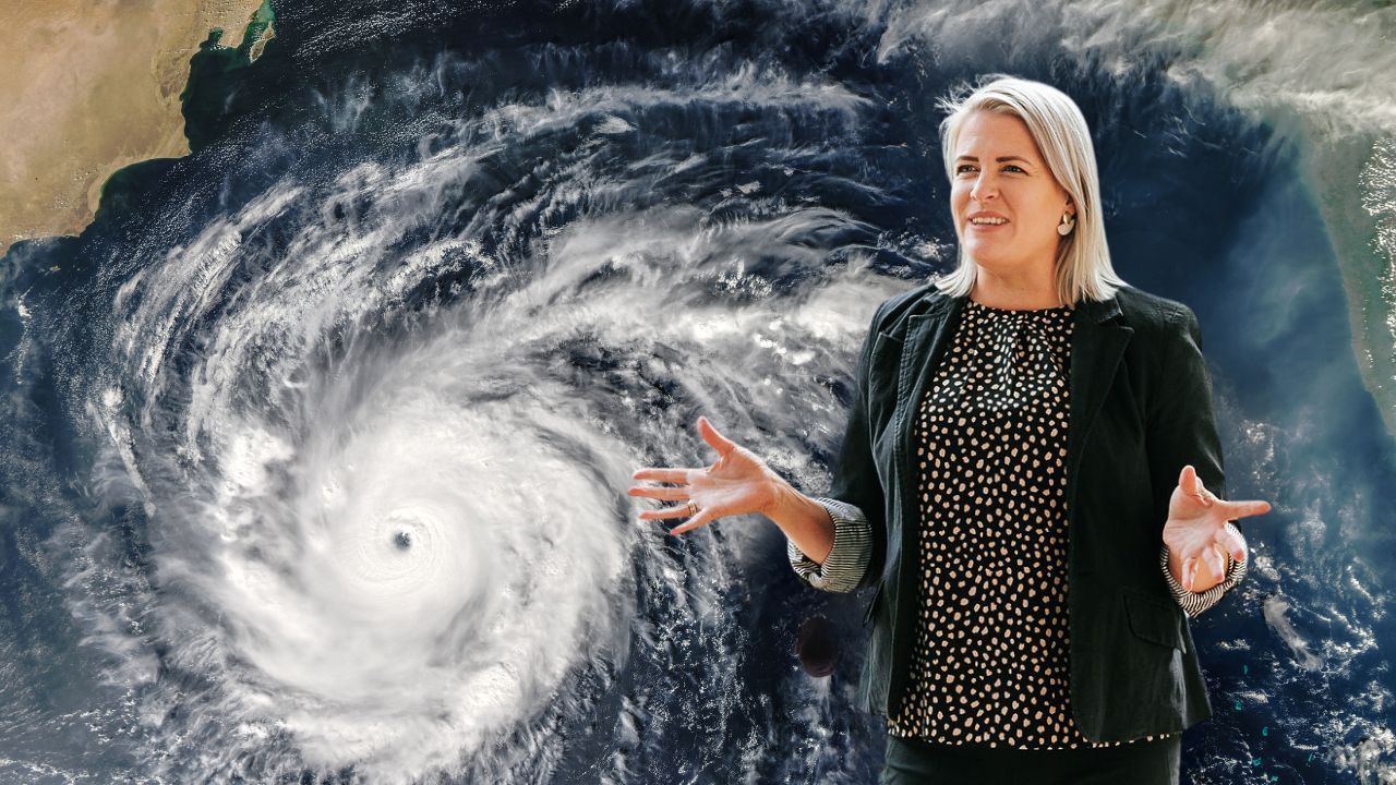 Meteorologist standing in front of an image of a cyclone.