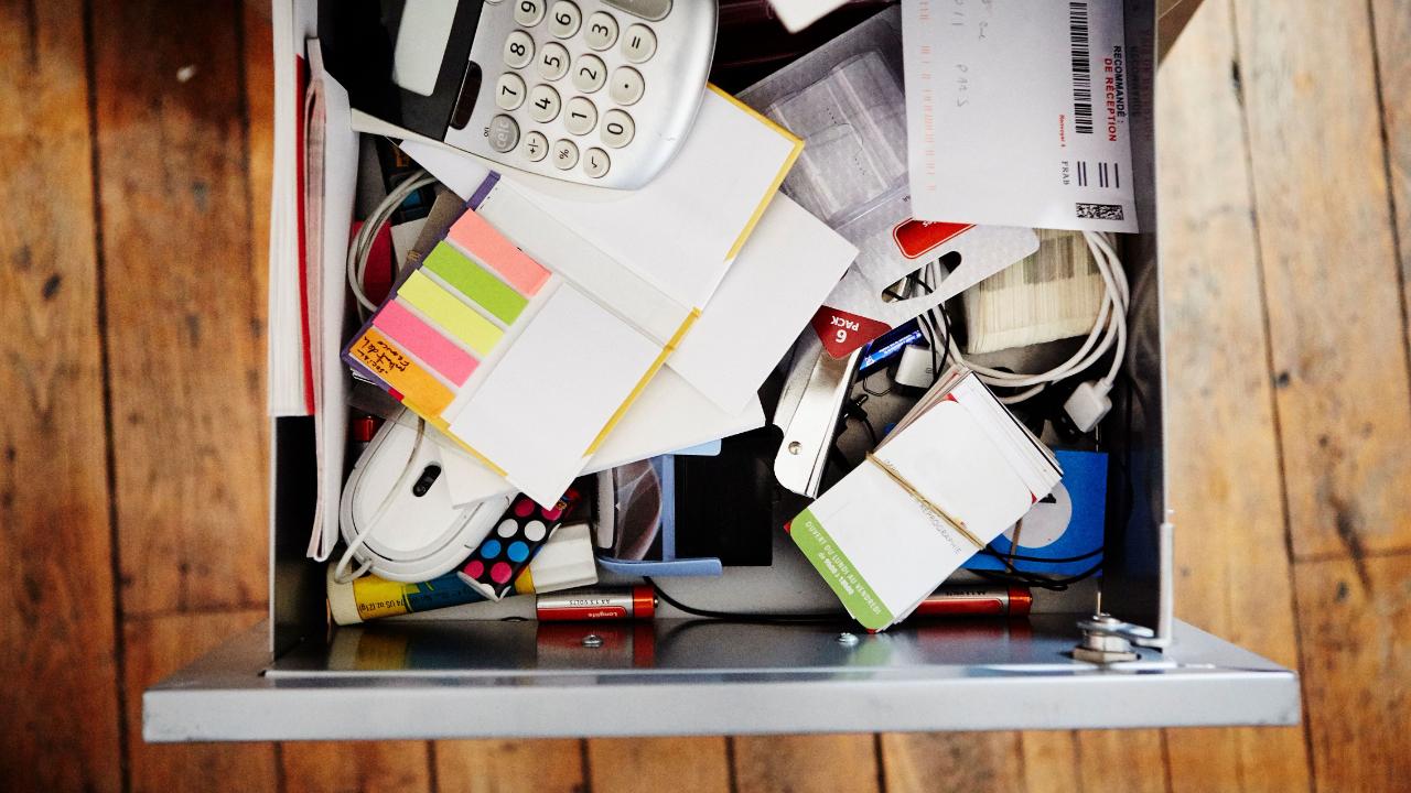 messy desk drawer overfilled with various business supplies