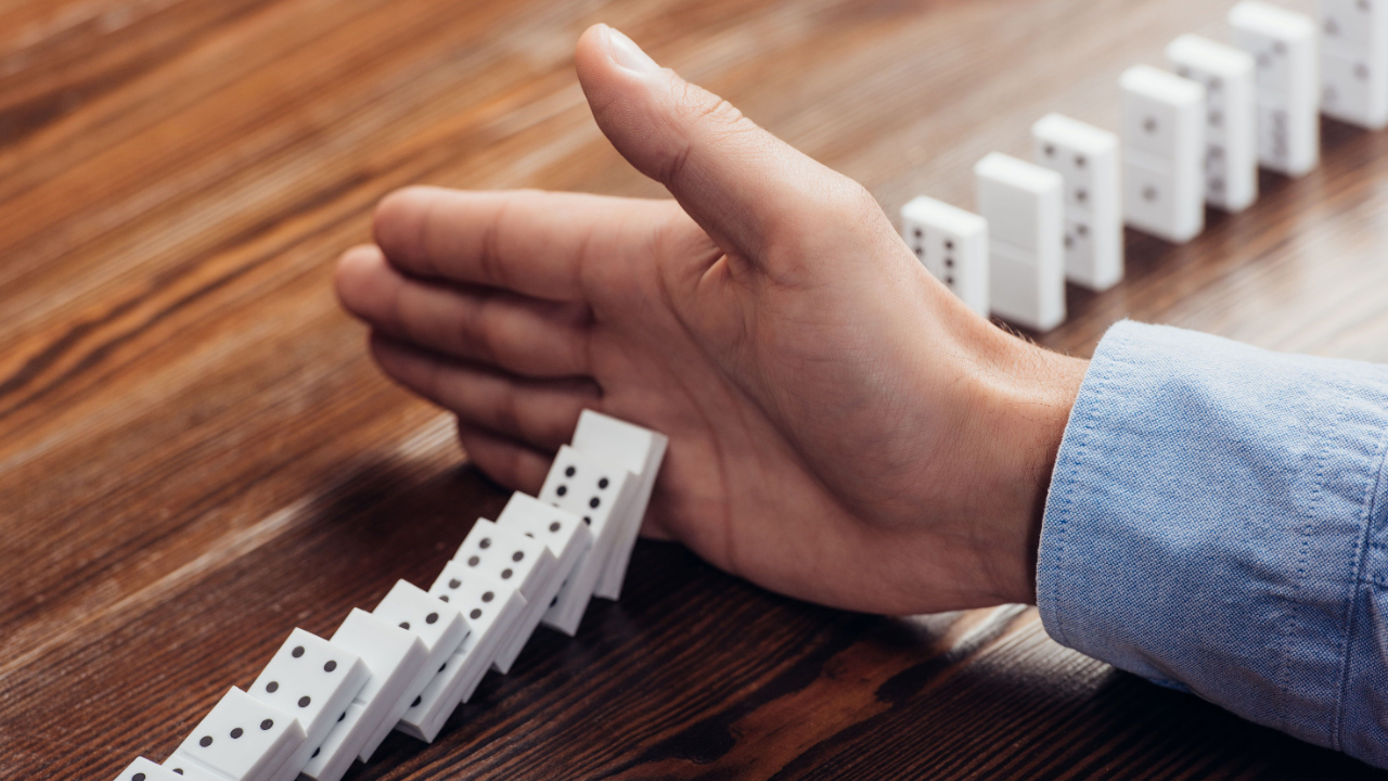 Man stops a line of dominoes from falling