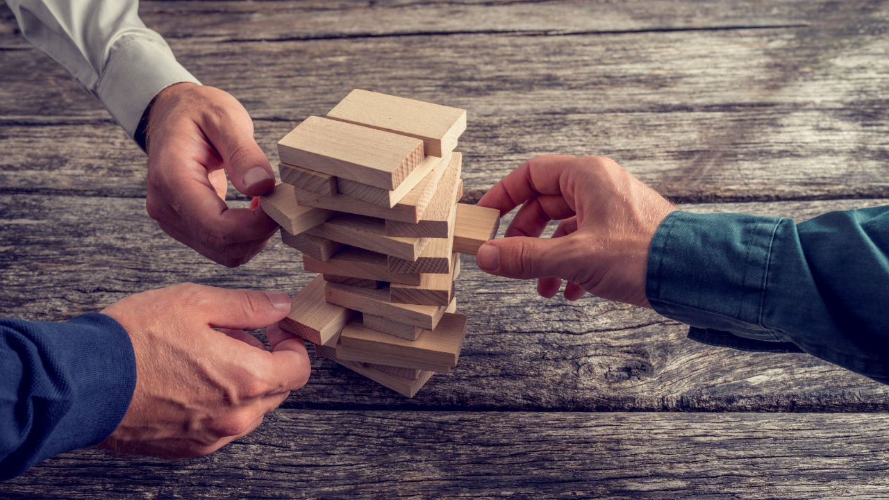 group of business men pulling Jenga blocks out of a pile