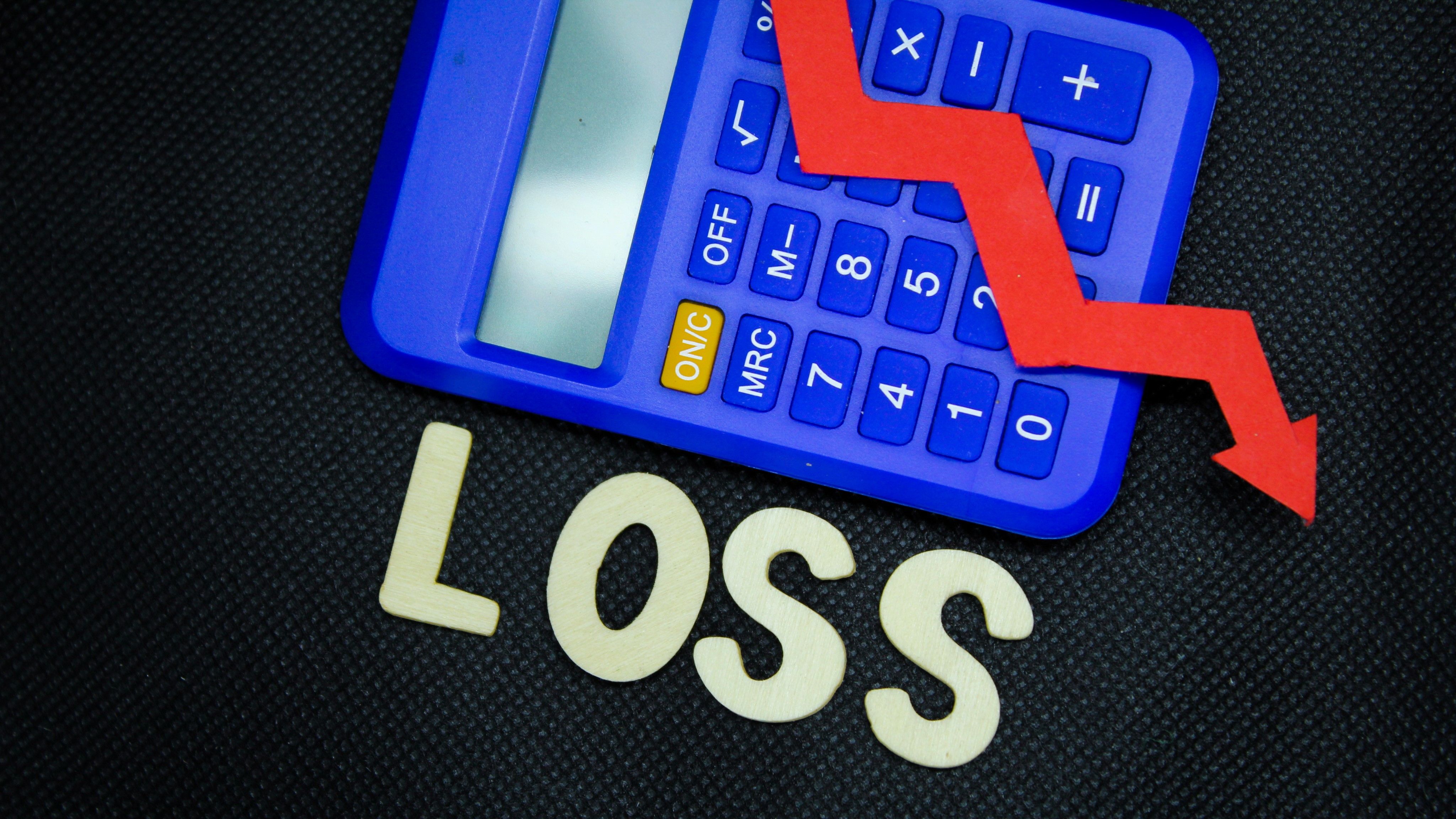 A calculator with an arrow going down showing profit loss