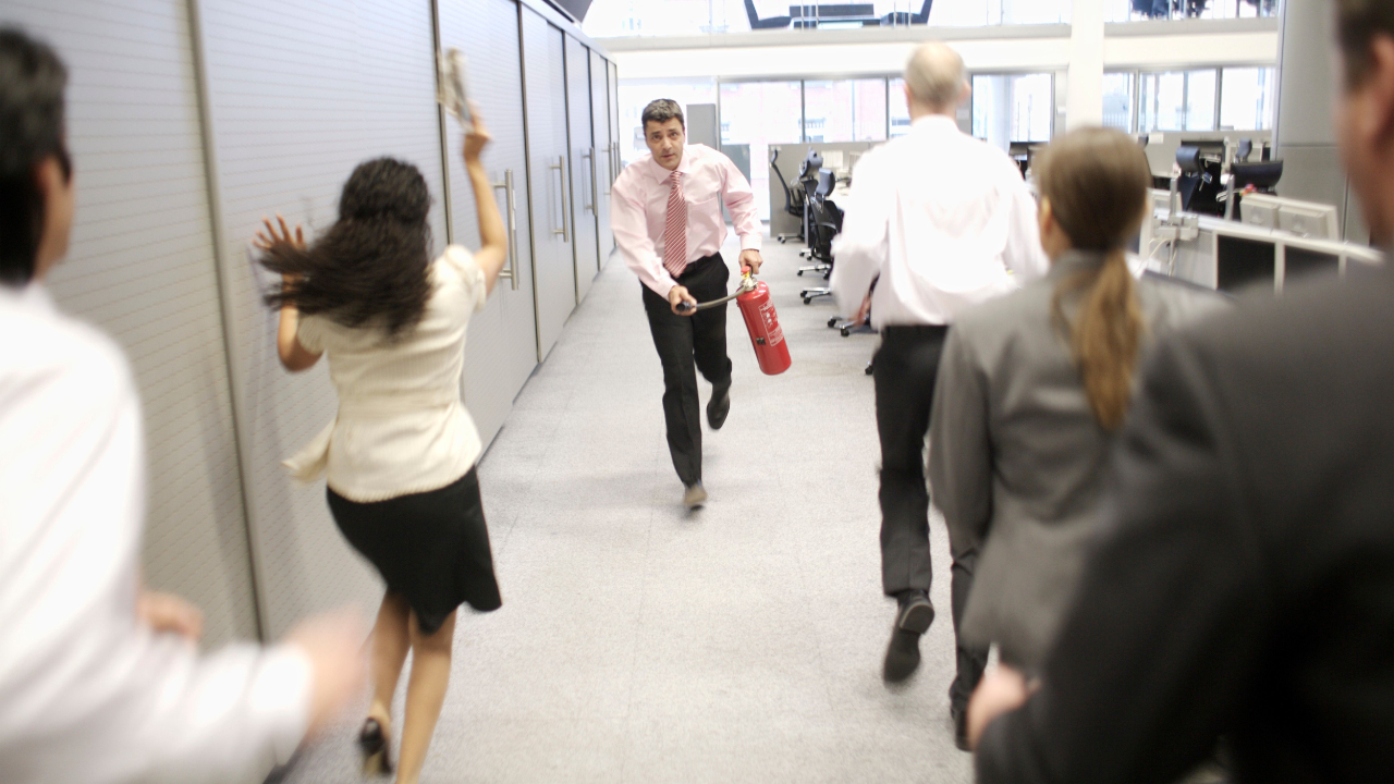 Businessman running through office with fire extinguisher