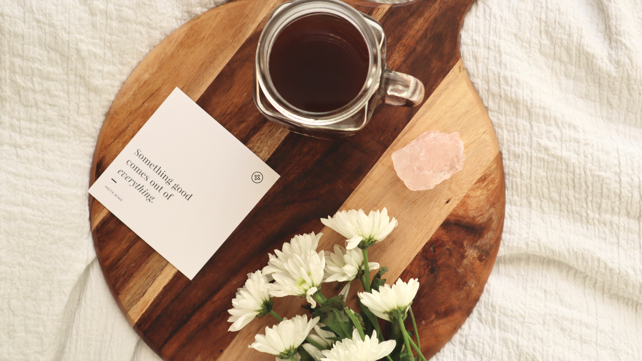 a tray with flowers, rose quartz, coffee cup and a positive affirmation note