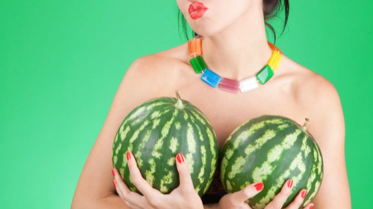 Faceless woman with big watermelons in front of her breasts