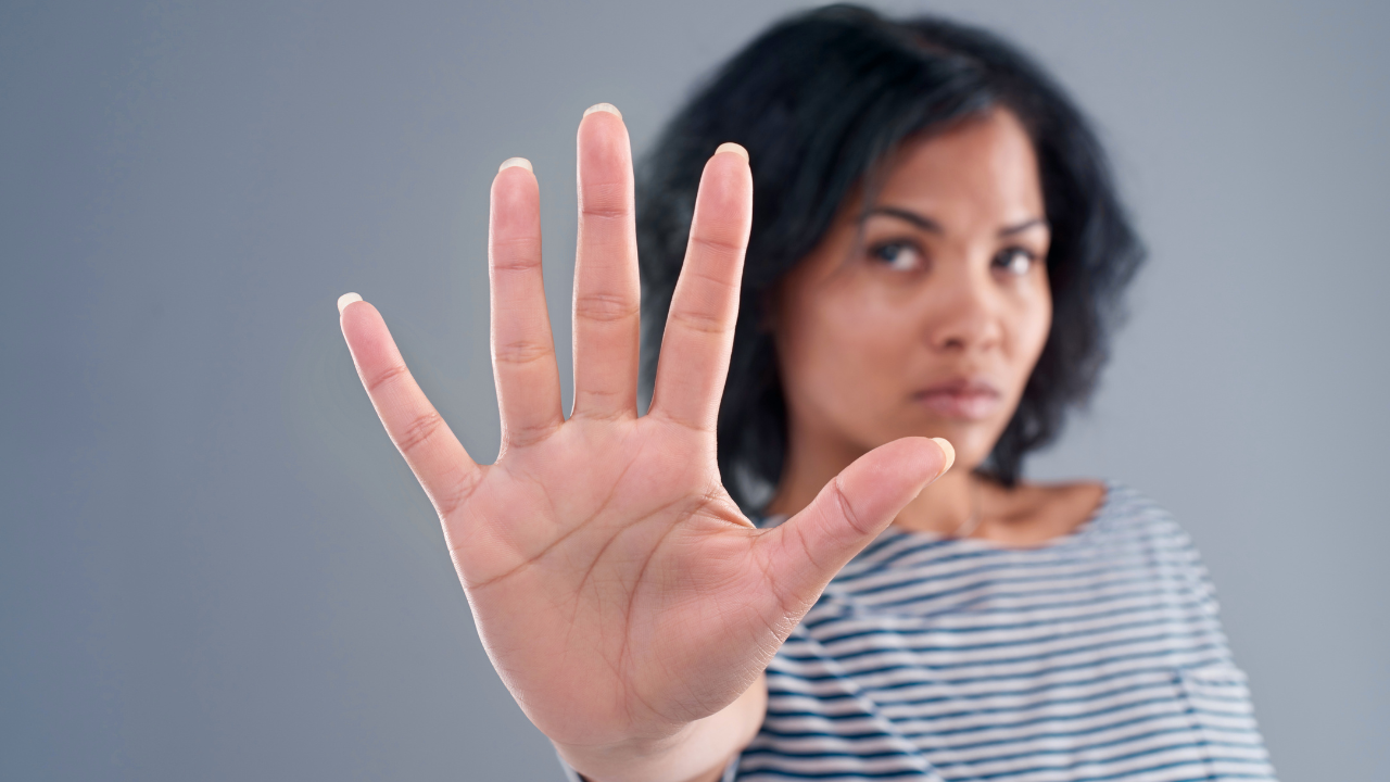 woman holding her hand up in a clear stop gesture, symbolizing healthy boundaries that protect energy, hormones, and wellbeing during the upgrade phase