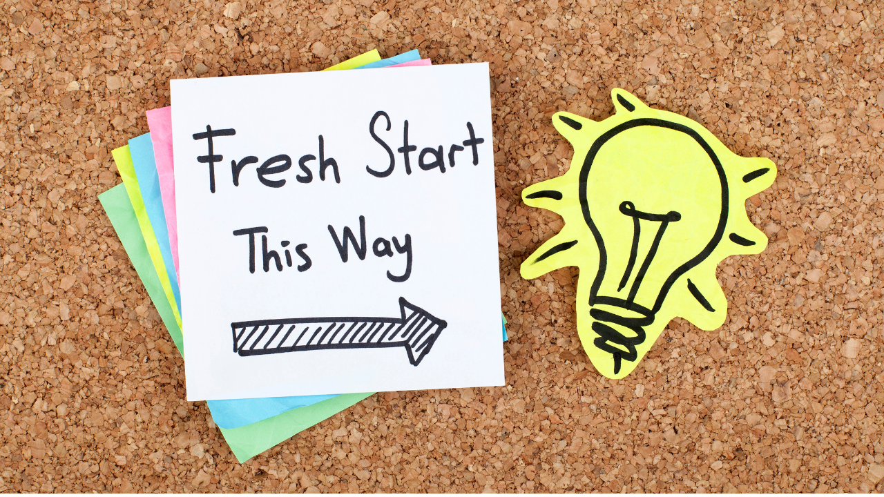 Fresh start note with an arrow pointing right beside a yellow lightbulb sketch pinned to a corkboard.