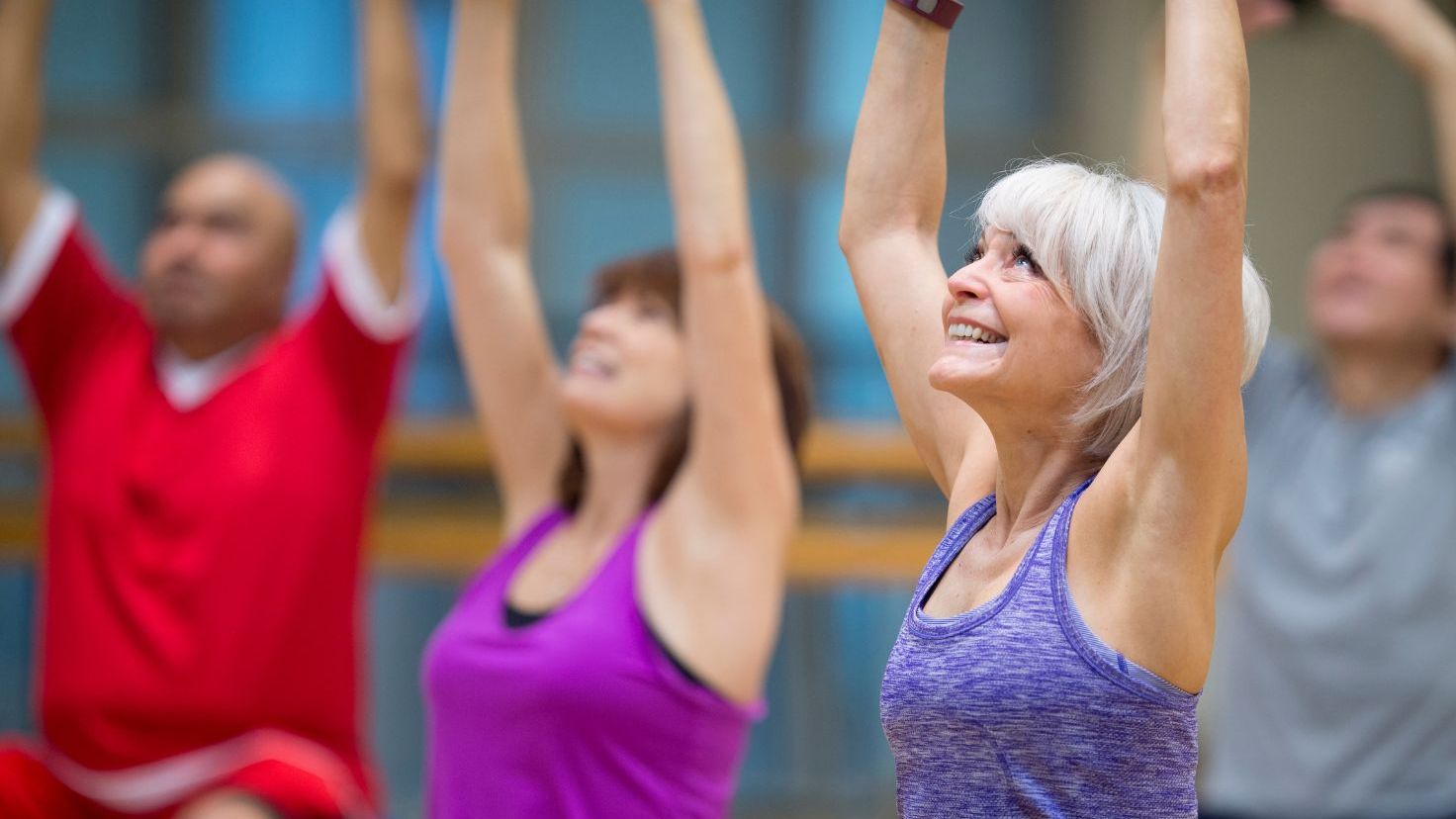 "Woman lifting her arms overhead during a group fitness class"