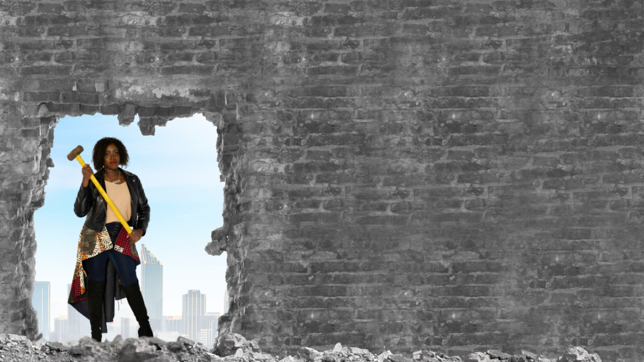 Woman standing in a broken brick wall opening, holding a sledgehammer, symbolizing strength, resilience, and the power to break through limitations and rebuild beyond adversity.