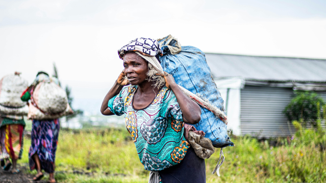 Woman carrying a heavy sack over her shoulders while walking forward, symbolizing the burden of strength, endurance, and the weight of constantly holding everything together.