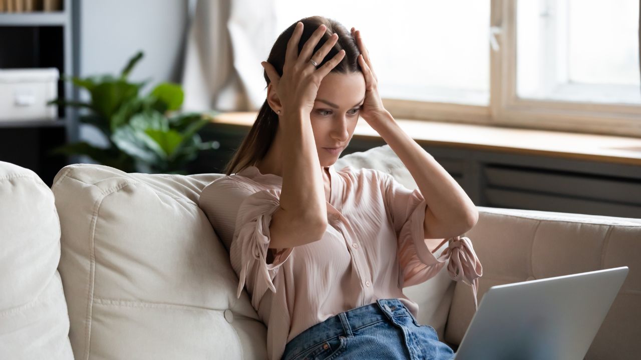 woman with hands on head looking at computer