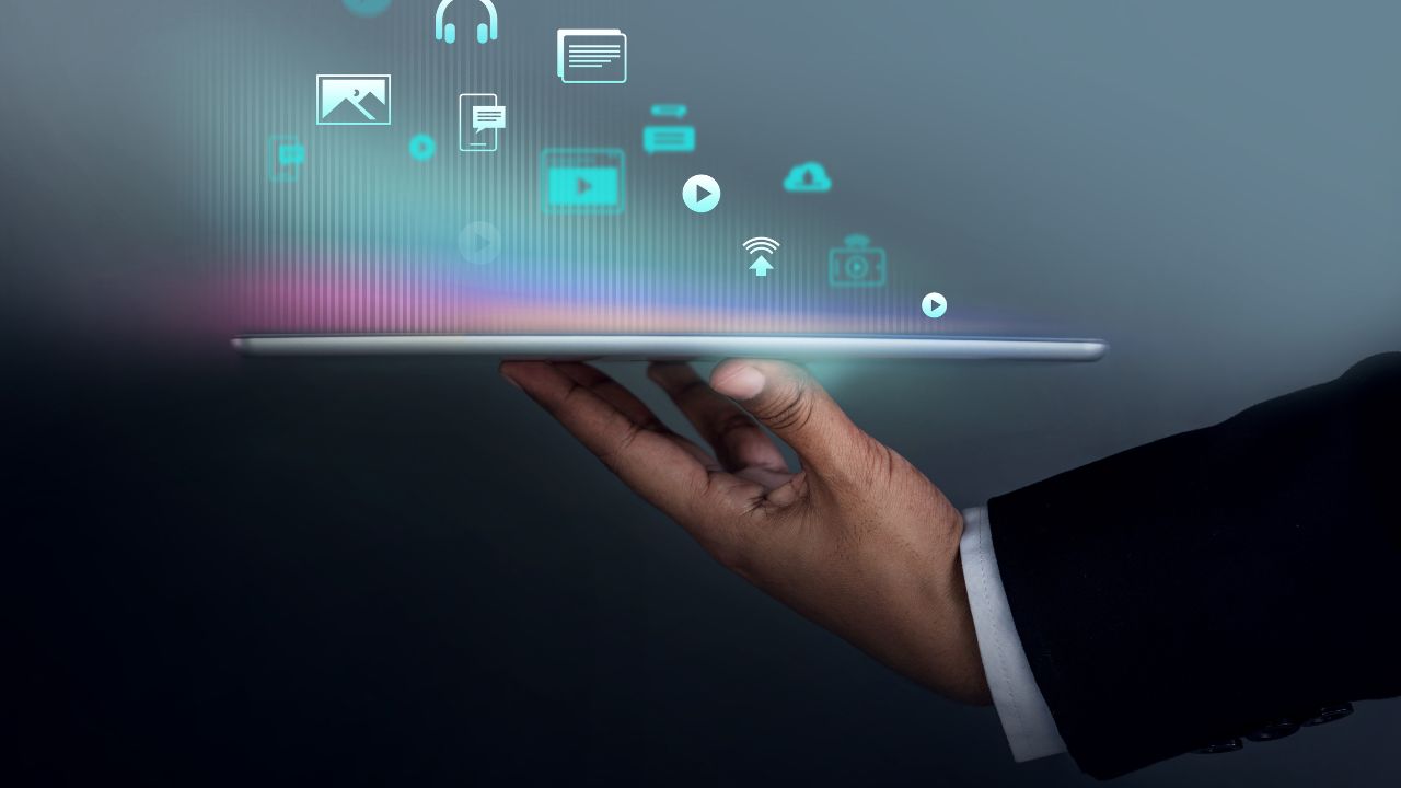 hand holding tablet with digital icons floating above