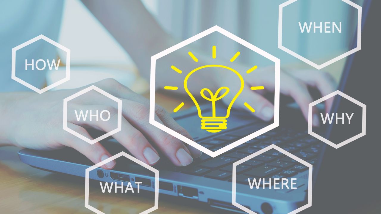 words who what where when why how and lightbulb floating above laptop with hands typing