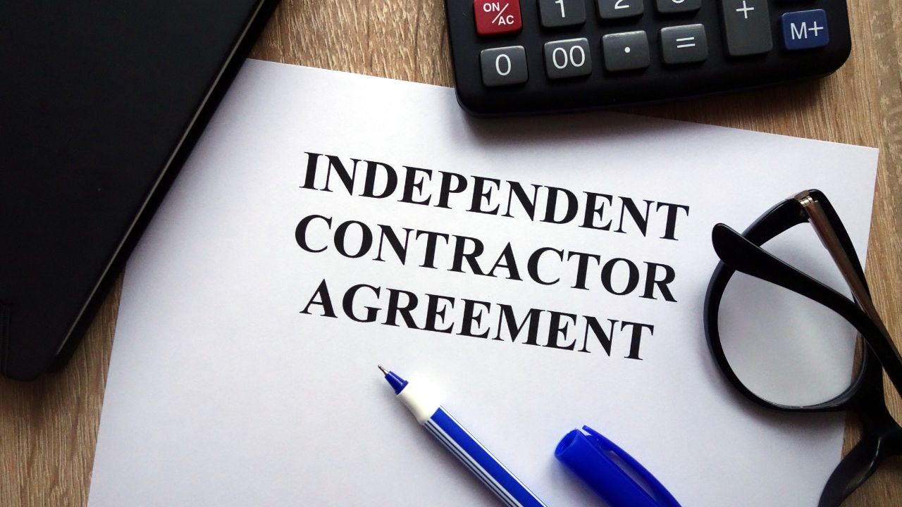  independent contractor agreement on desk with calculator and pen