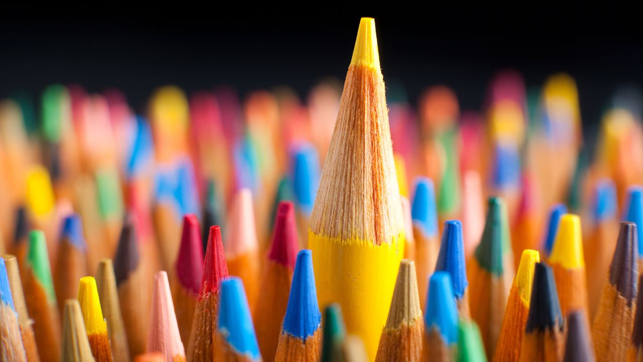 colored pencil tips with one yellow pencil tip above the crowd of pencil tips