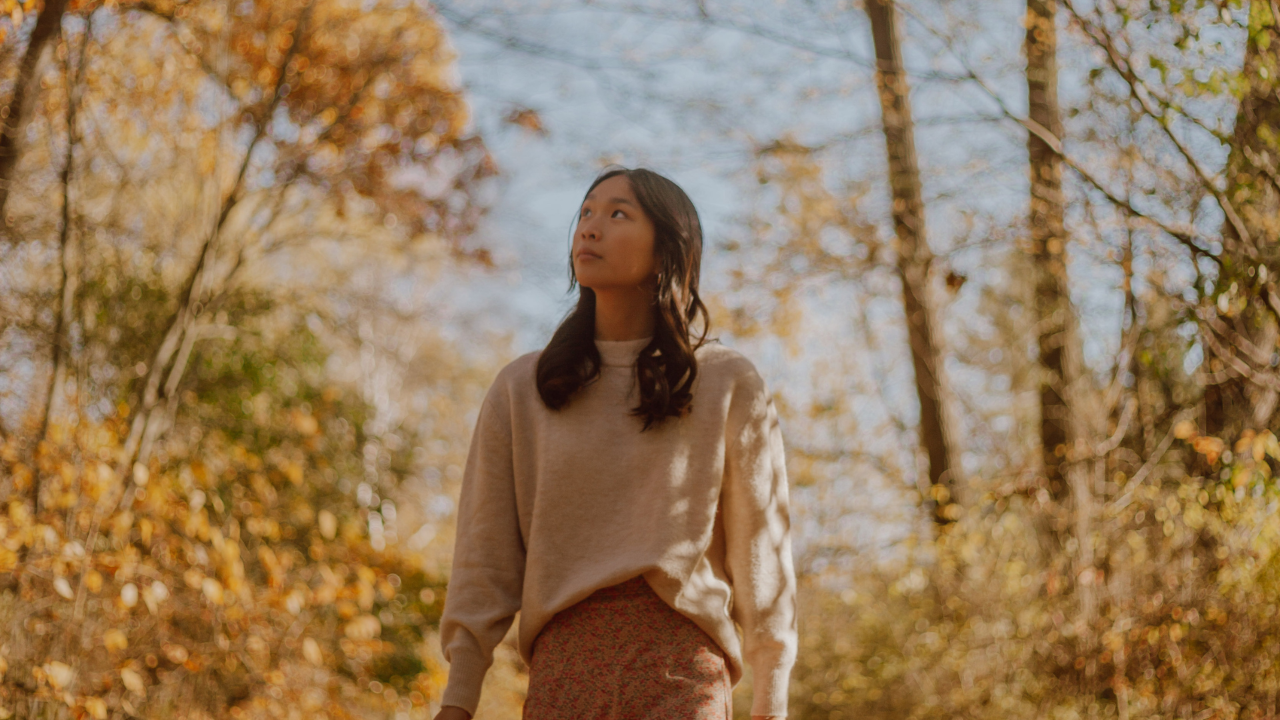 Vrouw loopt rustig door een stil bos, als symbool voor rust, gronding en ruimte bij hoogsensitiviteit.